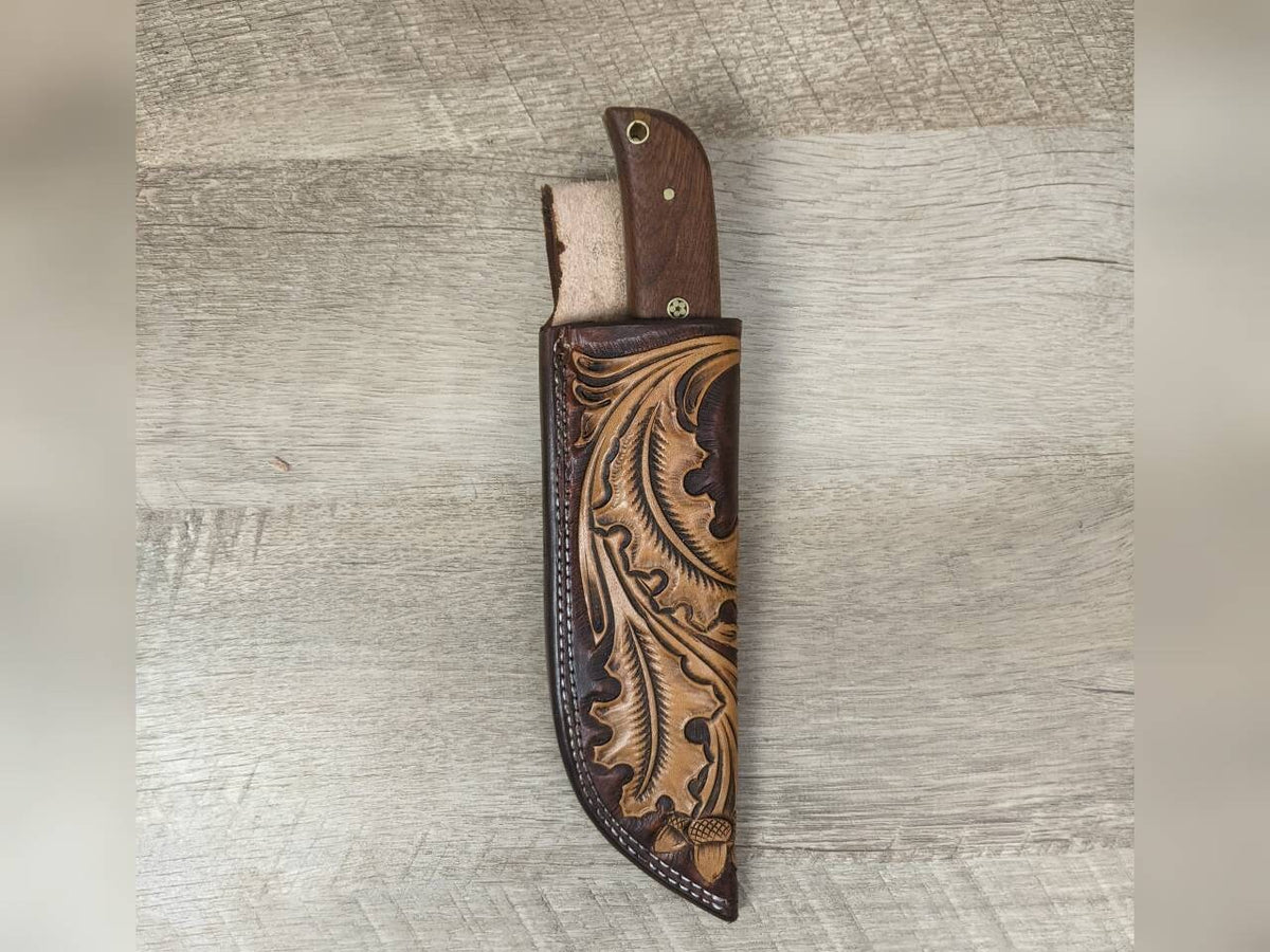 1095 forged hunting knife with a tooled oak leaf leather straight hang sheath